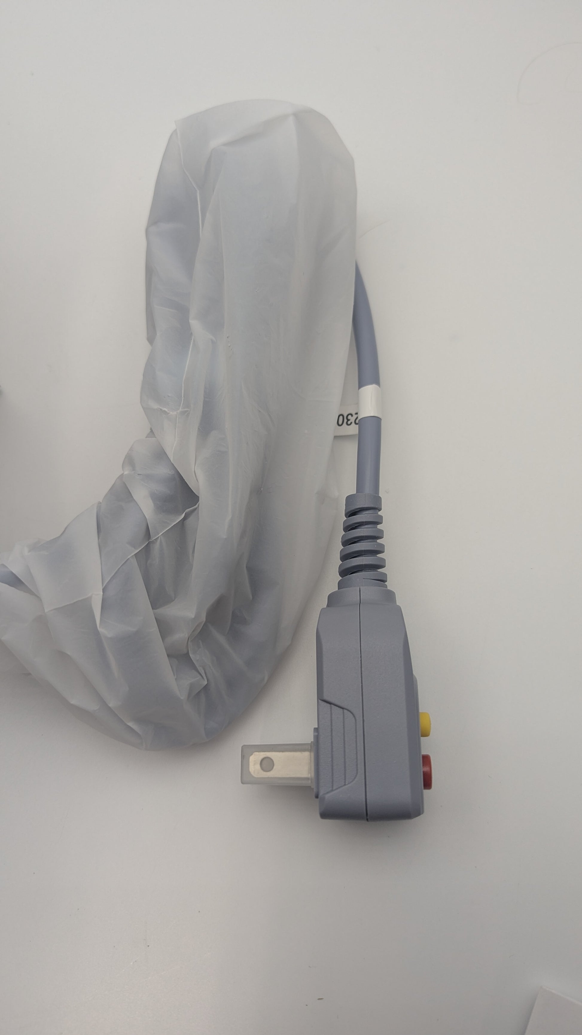 Gray power cord with plastic covering and plug on a white background.