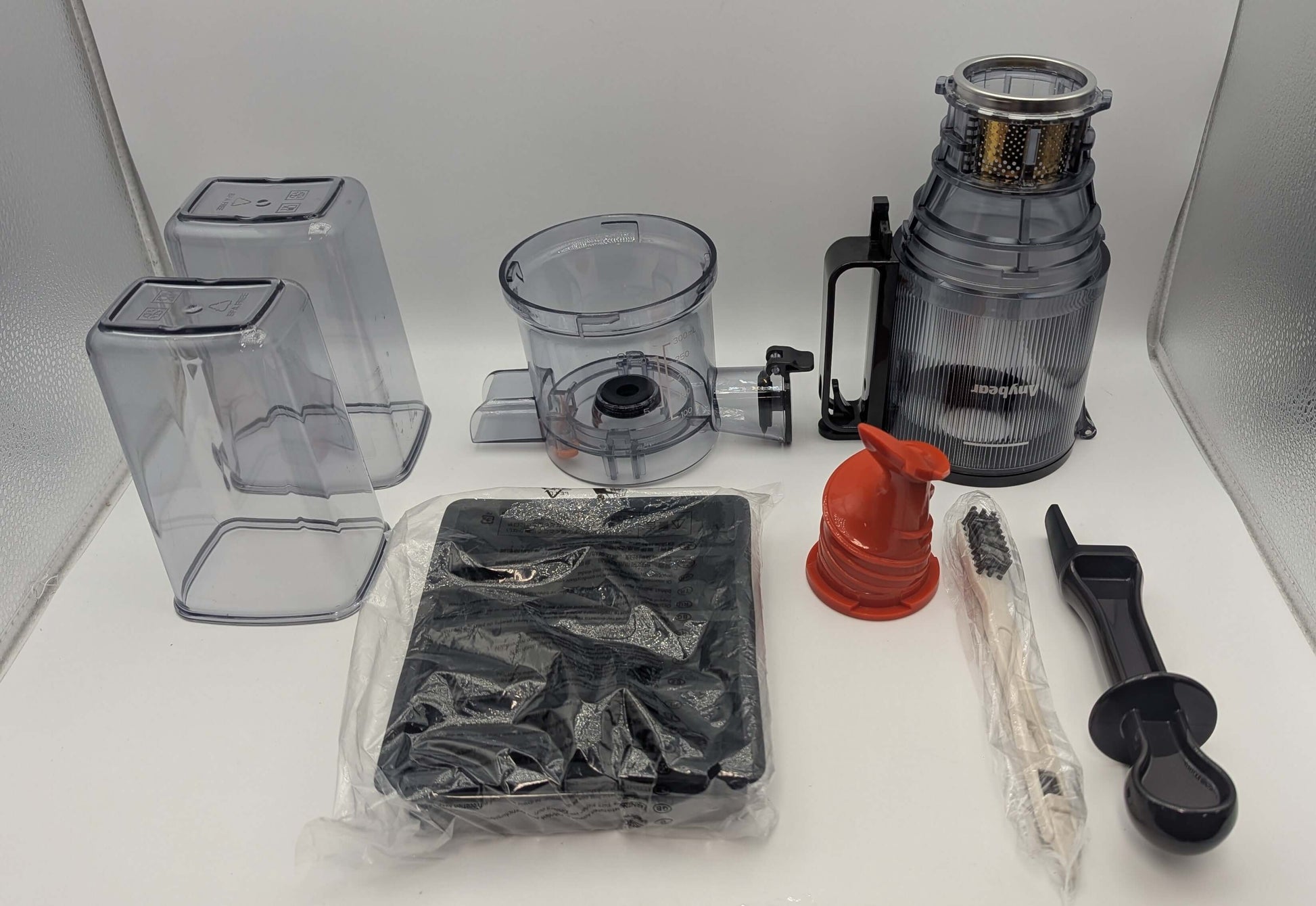 Anybear Cold Press Juicer parts including motor, chute, and accessories, displayed in silver and clear plastic materials.