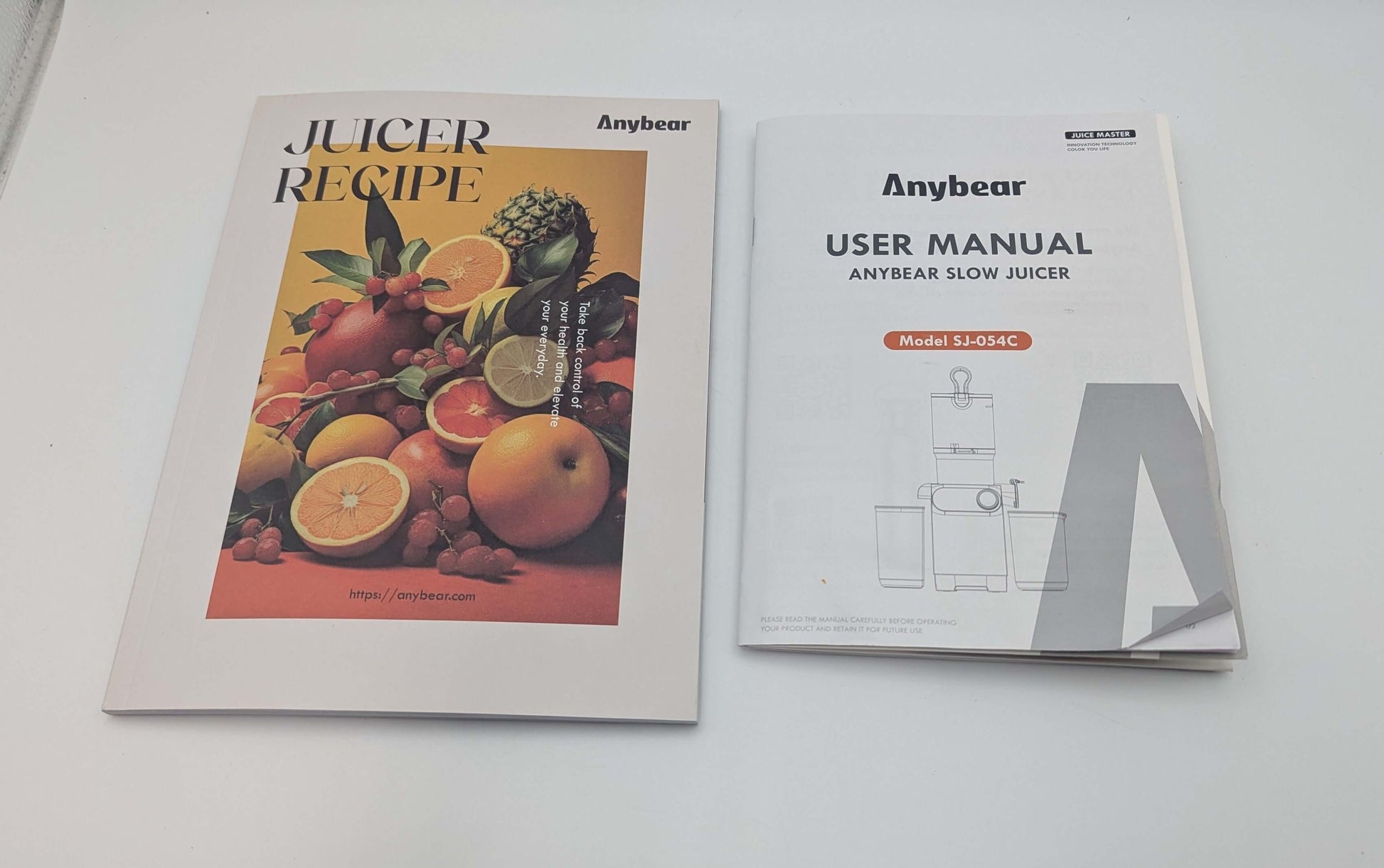 Anybear Slow Juicer user manual and recipe book on a white table.